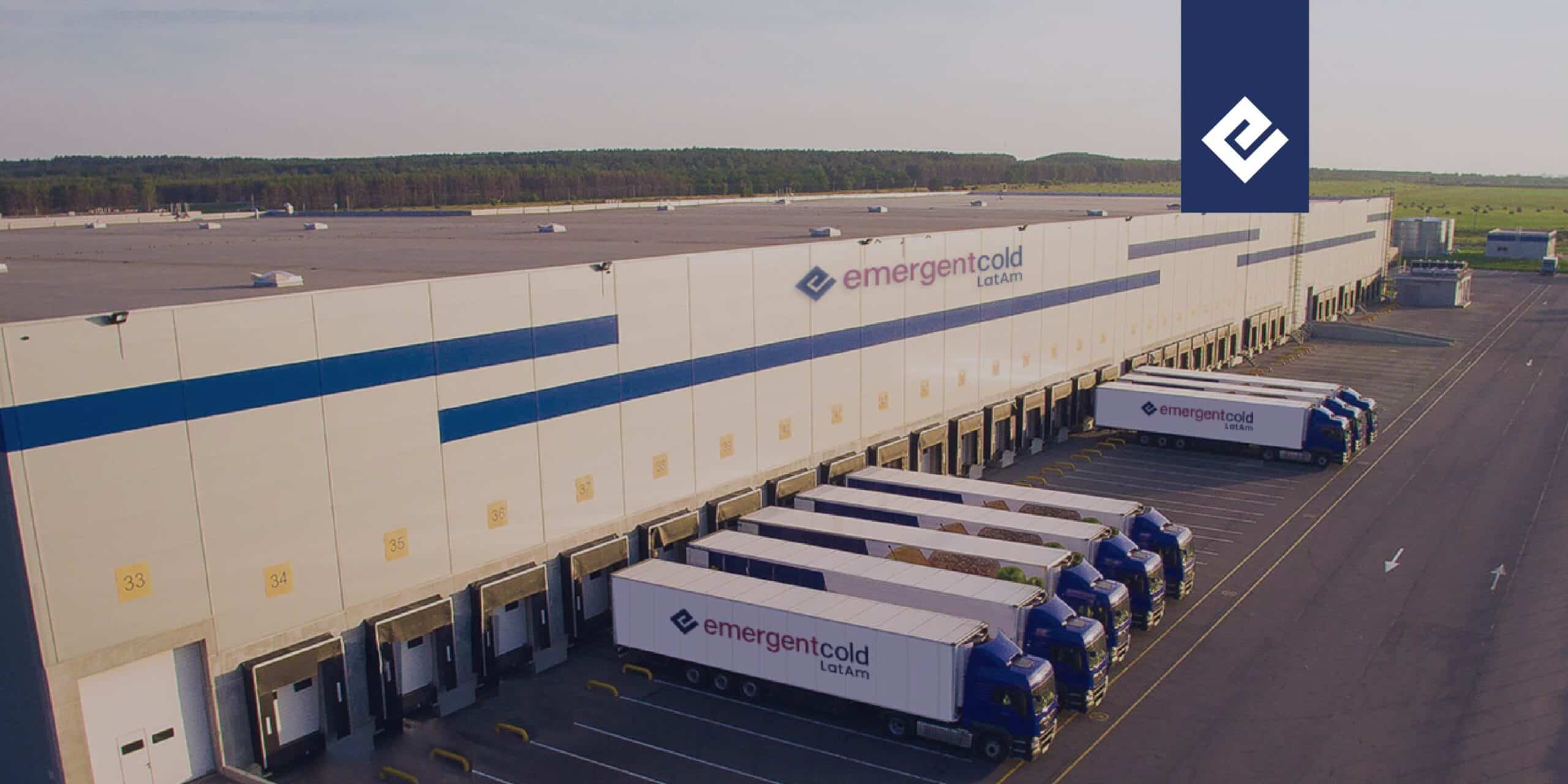 Almacén de Emergent Cold Latam con una flota de camiones estacionados frente a las puertas de carga y descarga.